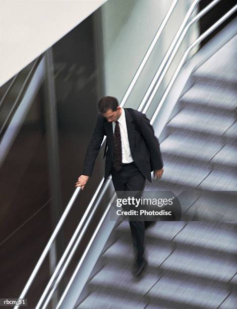 a businessman descends stairs beside a building - schwenk stock-fotos und bilder