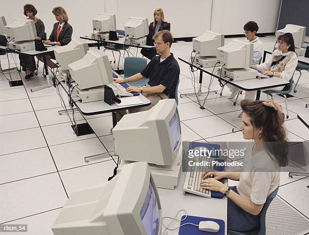 a group of people sit in front of computers in a white room as they learn how to use computers - how fotografías e imágenes de stock
