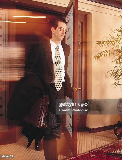 a blurred and suited businessman exits an office through a wood and glass door - door stockfoto's en -beelden