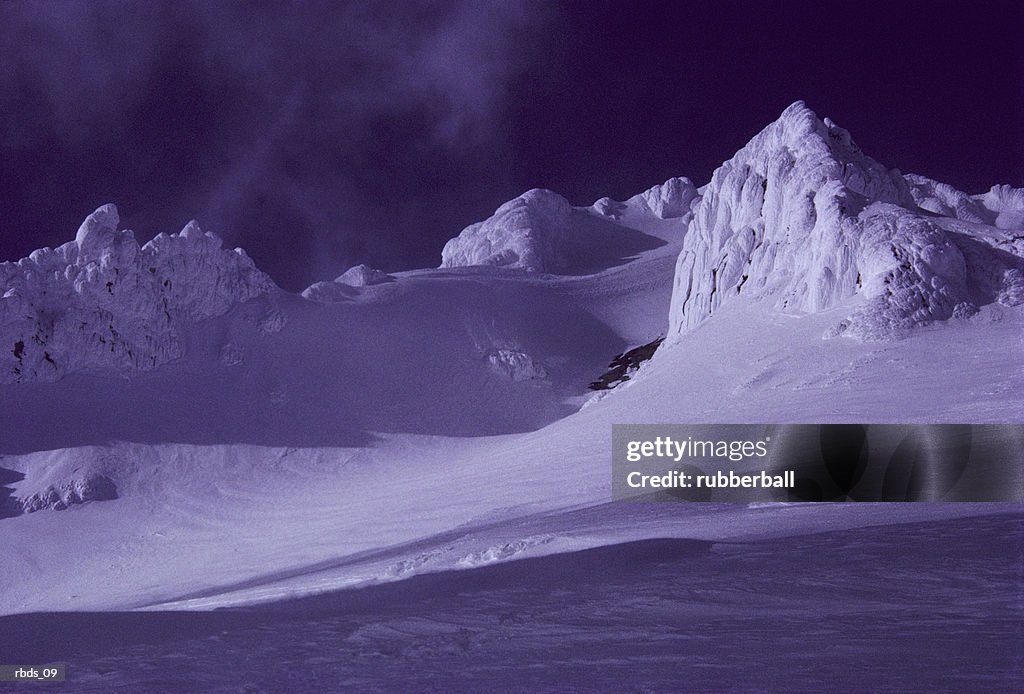 A blue snow covered mountain range at night