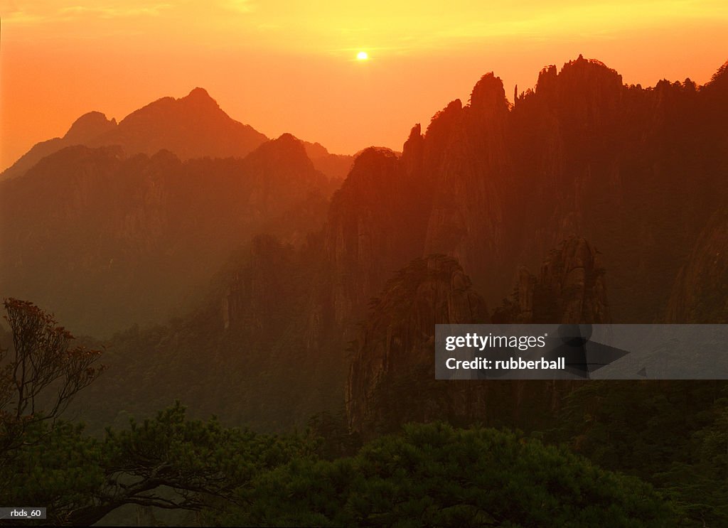 Asian silhouetted mountains against a yellow and orange sunset