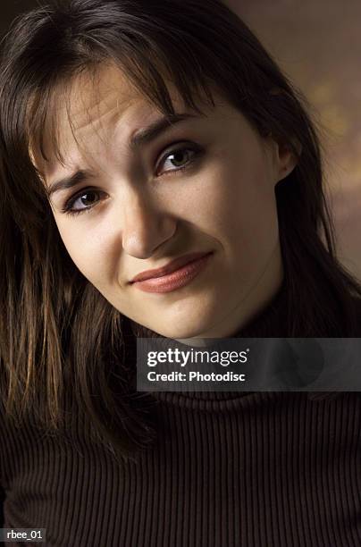 a young caucasian brunette woman in a dark turtleneck has an expression of disgust as she raises one eyebrow - turtleneck stock pictures, royalty-free photos & images