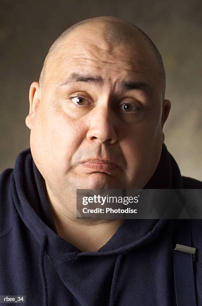 a large size caucasian man with shaved head and wearing a blue sweatshirt is frowning sadly - shaved head ストックフォトと画像