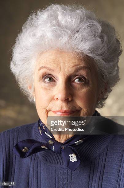 an elderly caucasian woman with curly white hair is wearing a blue sweater and looking smugly upward - curly stock pictures, royalty-free photos & images