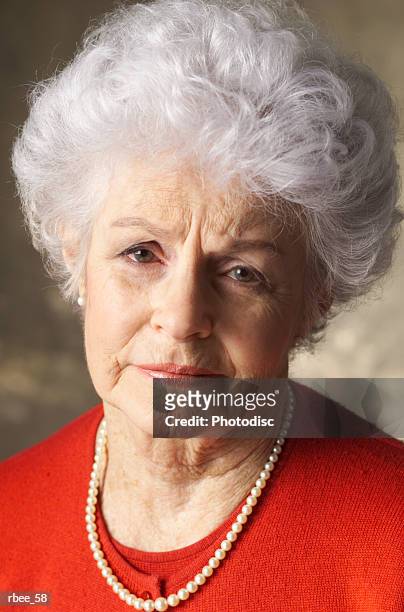 an elderly caucasian woman with curly white hair is wearing a red shirt and has an expression of sadness - curly stock pictures, royalty-free photos & images