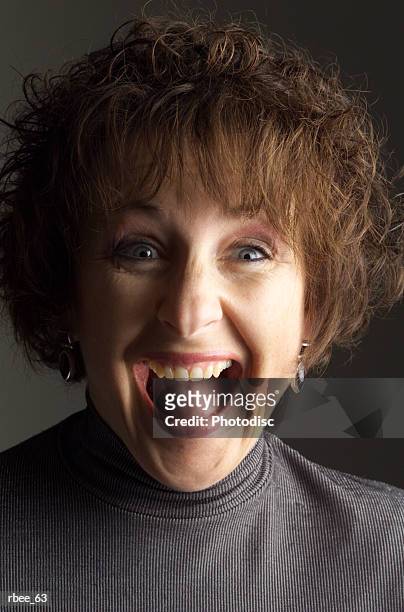 a middle aged woman with curly brown hair is wearing a gray sweater and yelling happily - curly stock pictures, royalty-free photos & images