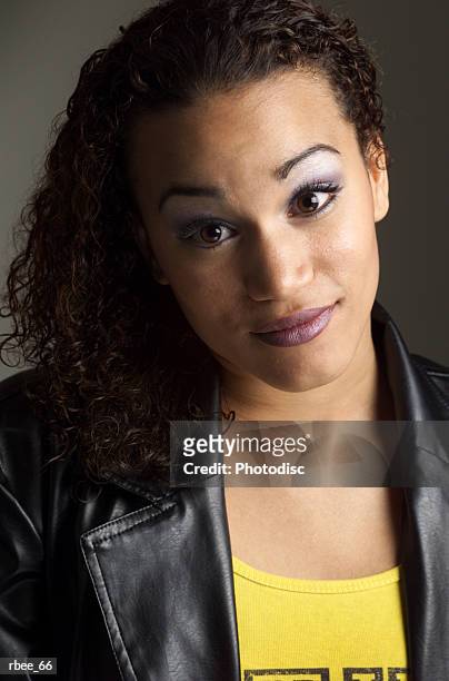 a pretty young ethnic woman wearing a leather jacket has very curly long hair and is smiling shyly - curly stock pictures, royalty-free photos & images