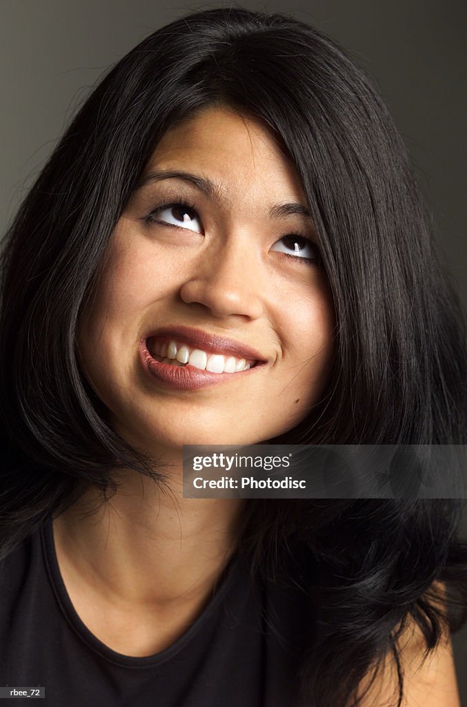Pretty young asian woman long black hair wears dark shirt bites lower lip looks upward nervously