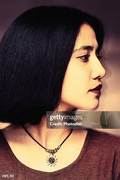 happy female woman with shorter straight dark hair and red lipstick wearing a maroon dress and necklace looks to her left revealing her stunning profile - happy stockfoto's en -beelden