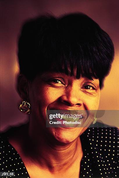 happy african-american woman with short black hair wearing a black and white polka-dot dress or shirt and earrings smiles - dot photos et images de collection