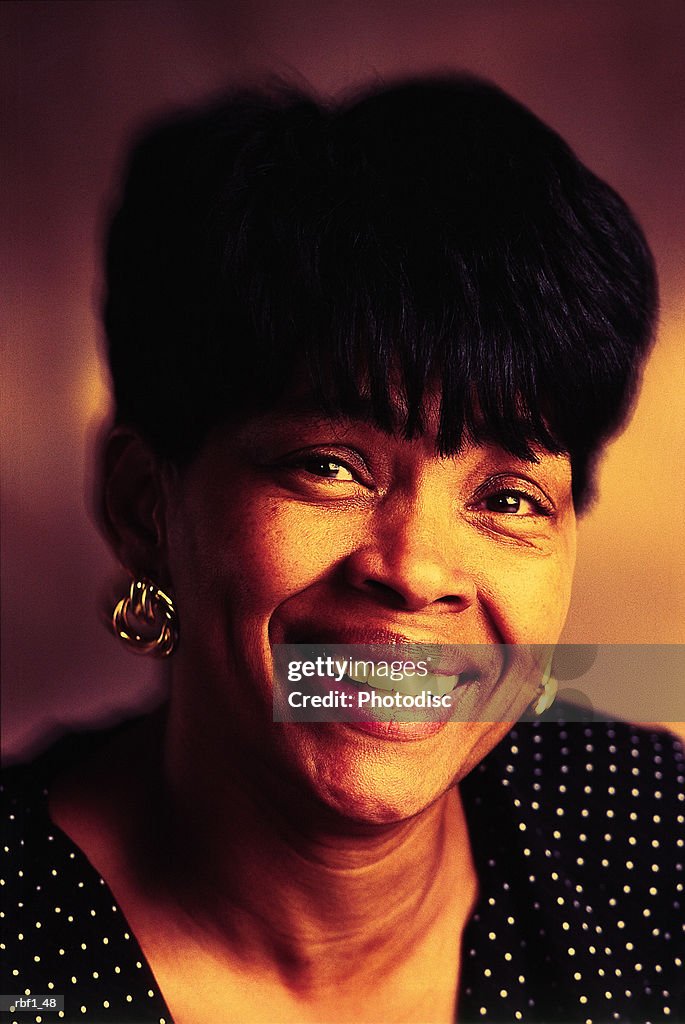 Happy african-american woman with short black hair wearing a black and white polka-dot dress or shirt and earrings smiles
