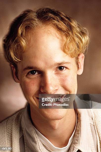 happy young man in his 20_s with curly blonde hair wearing a tan shirt smiles - curly stock pictures, royalty-free photos & images