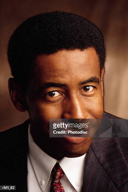 happy fun african-american male man with dark hair and a friendly smile wearing a dark suit white shirt and tie smiles and turns his head to his left - happy stockfoto's en -beelden
