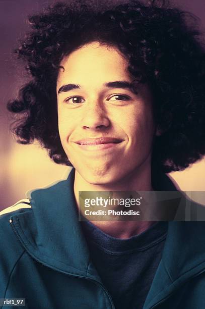 portrait of a teenage male with curly hair and a blue jacket as he smilies slightly - curly stock pictures, royalty-free photos & images