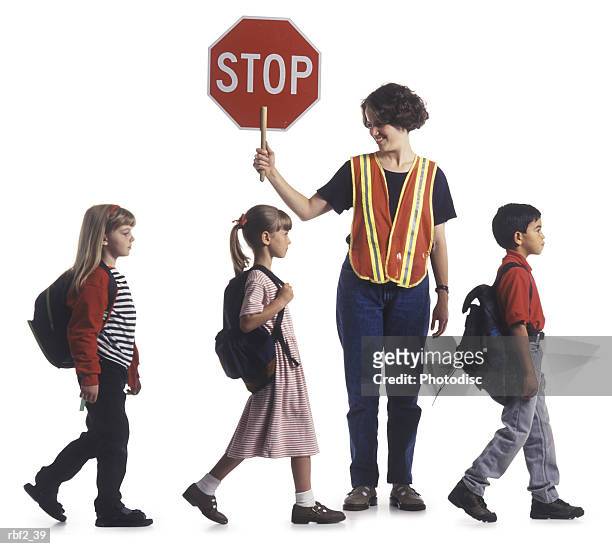a group of children walk in a line while assisted by a crossing guard - 交通誘導員 ストックフォトと画像