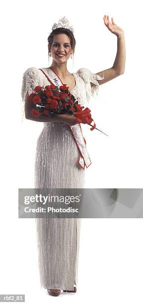a young adult female beauty pageant contestant with flowers and a tiara waves at the camera - beauty pageant crown stock-fotos und bilder