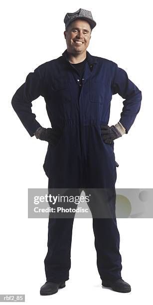 an adult male engineer in a blue jumpsuit and hat as he puts his hands on his hips and smiles - mining hats stock pictures, royalty-free photos & images