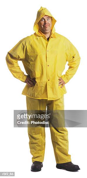 an adult male in a yellow rain gear puts his hands on his hips and smiles - レインコート ストックフォトと画像