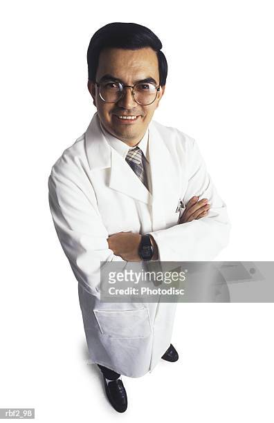 a man dressed in a white lab coat crosses his arms as he looks up toward the camera - lab coat stock-fotos und bilder