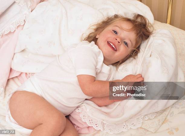 a young redheaded girl lays in bed as she smiles and snuggles up to a blanket - olivia wilde co hosts event at birchbox soho in celebration of conscious commerce birchbox collaboration stockfoto's en -beelden