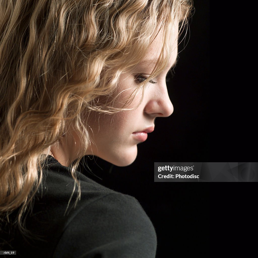 Portrait of a teenage blonde caucasian girl in a black shirt as she turns her head in profile displaying a serious look