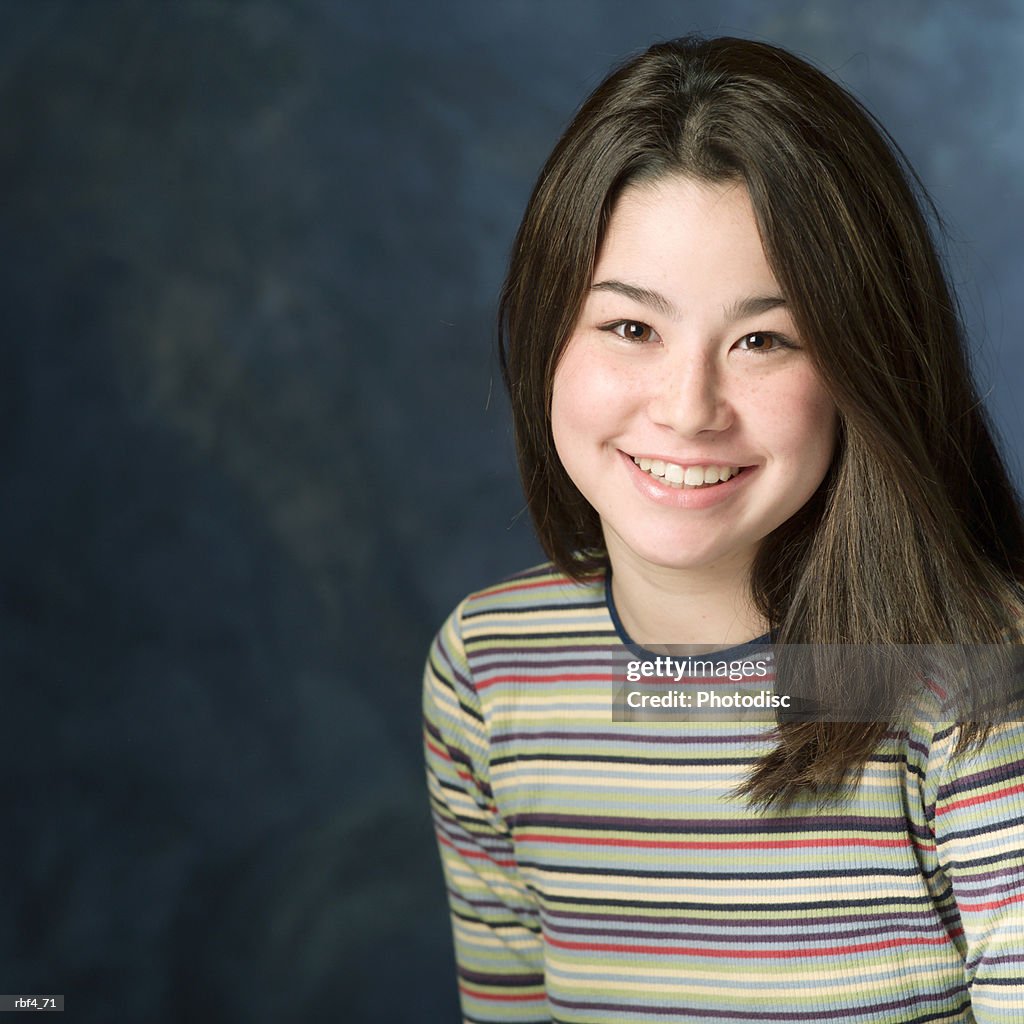 Portrait of a teenage asian girl in a multi colored sweater as she smiles at the camera