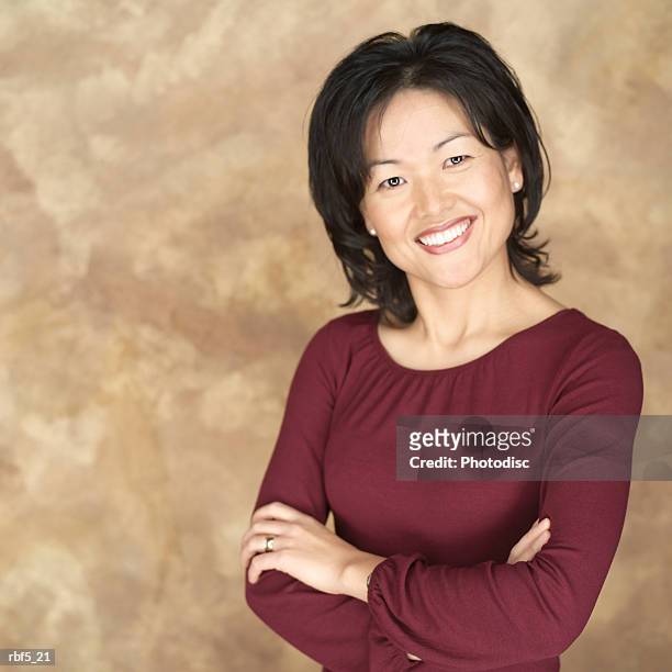 portrait of an attractive asian woman in a maroon blouse as she folds her arms smiles into the camera - maroon - fotografias e filmes do acervo