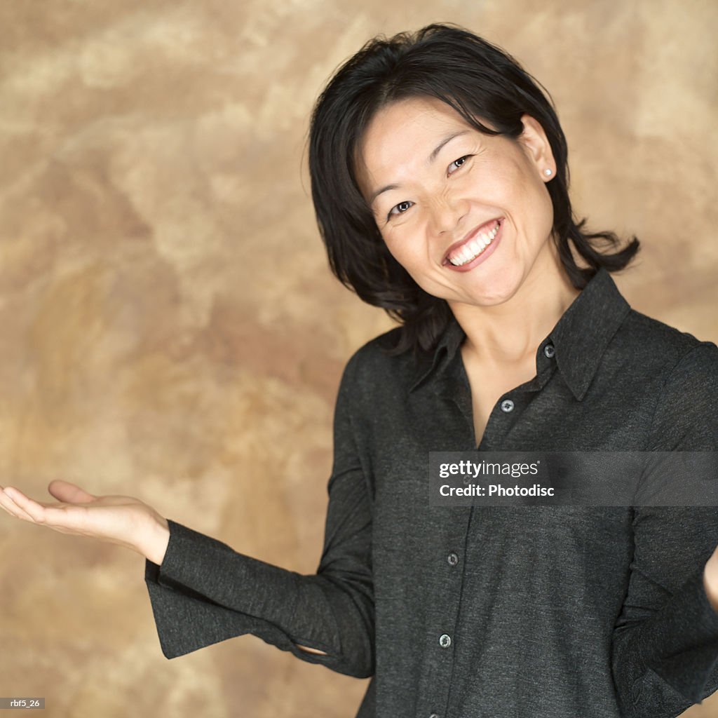 Portrait of an attractive asian woman in a black shirt as she gestures with her arm and smiles