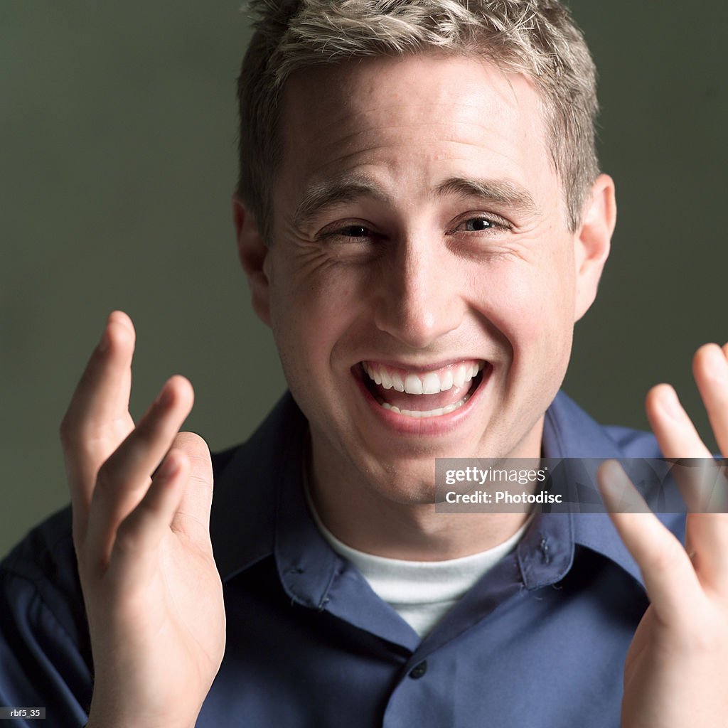 Portrait of a young caucasian man in a blue shirt as he gestures with his hands and laughs