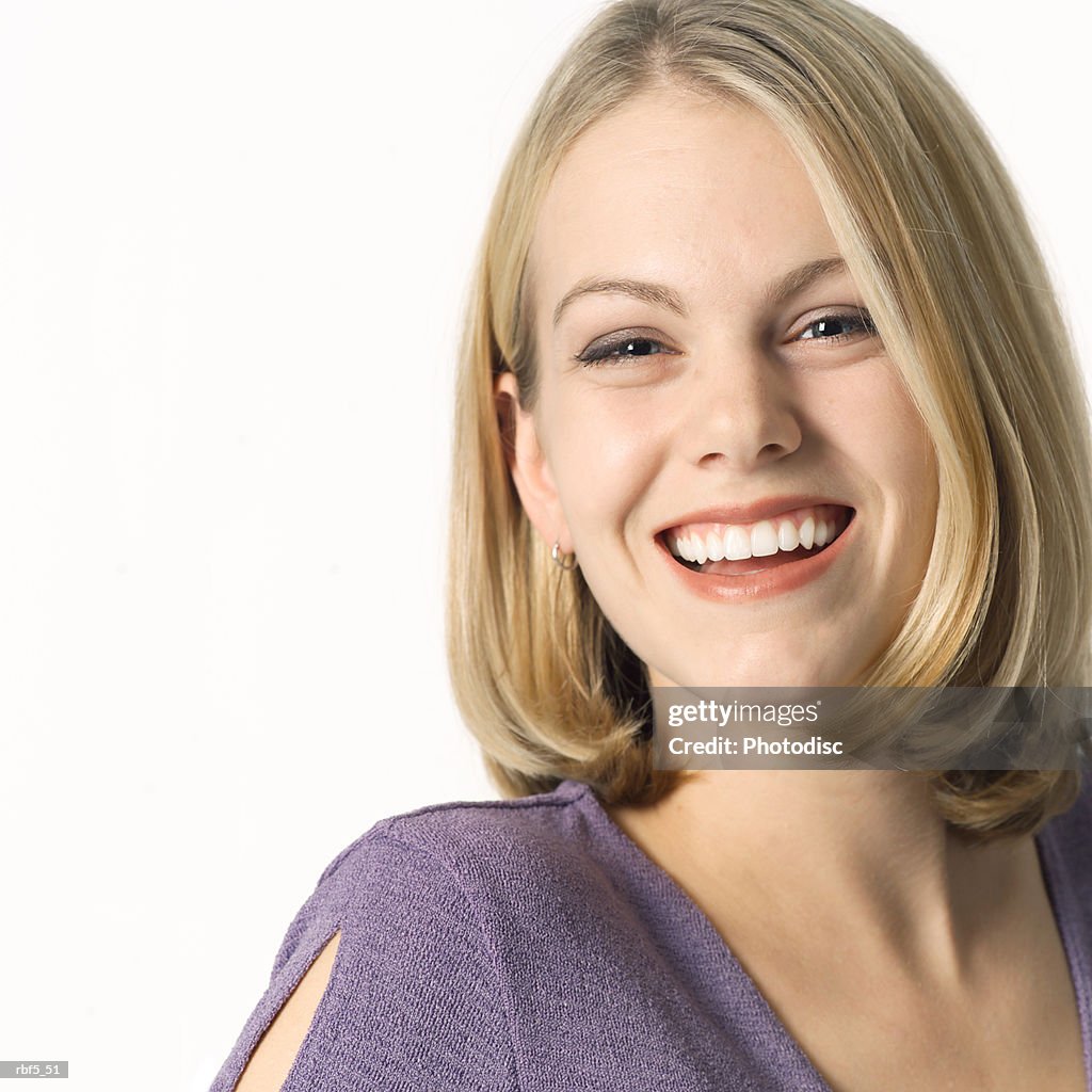 Portrait of a young blonde caucasian woman in a purple blouse smiles and laughs into the camera