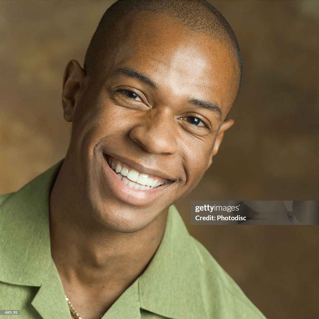 Portrait of a young african american man in a green shirt as he smiles big into the camera