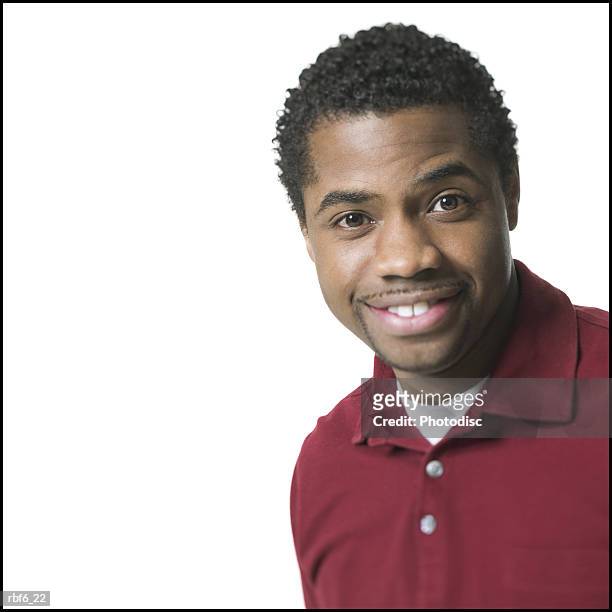 portrait of a young adult male in a red shirt as he smiles brightly - african male red shirt stock-fotos und bilder