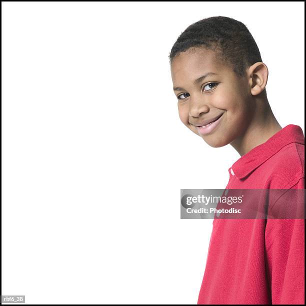 portrait of a male child in a red shirt as he turns and flashes a devilish smile - african male red shirt stock-fotos und bilder