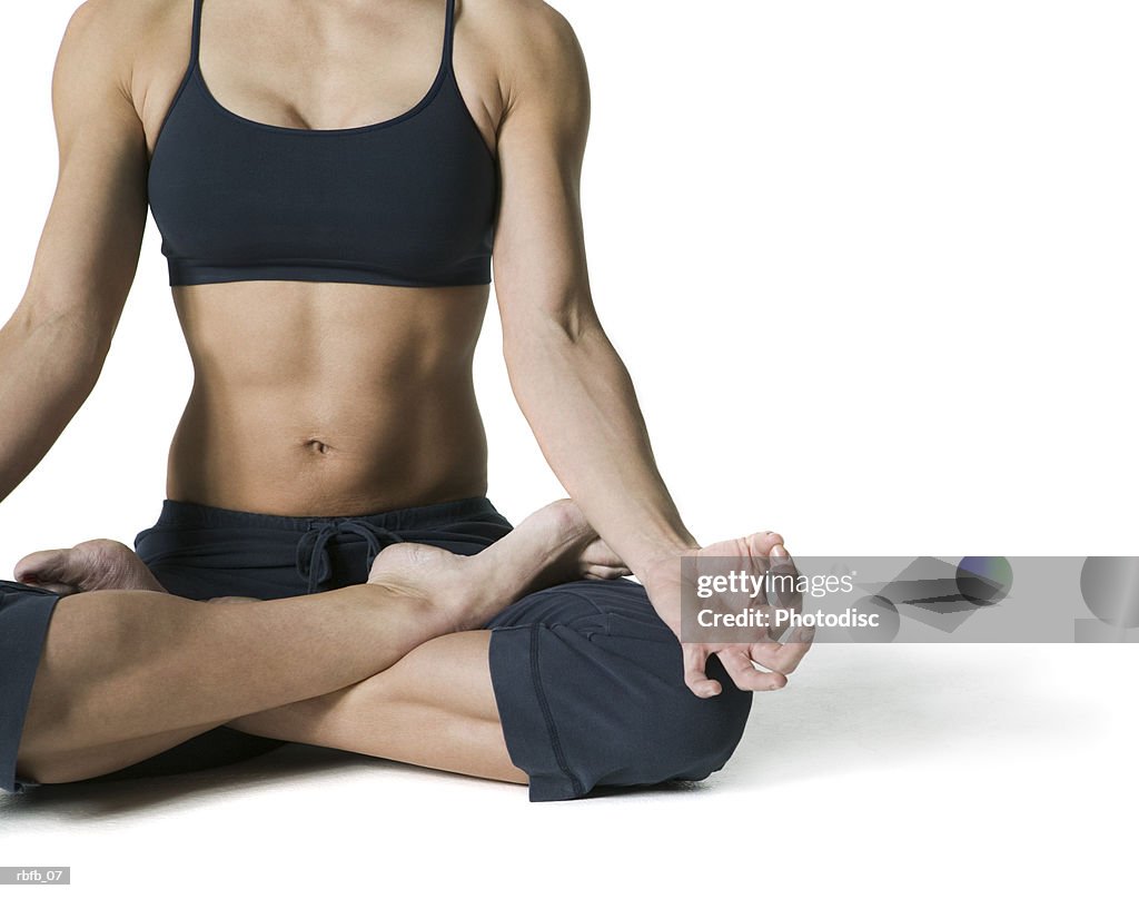 Medium shot of an adult woman in a workout outfit as she sits and does yoga