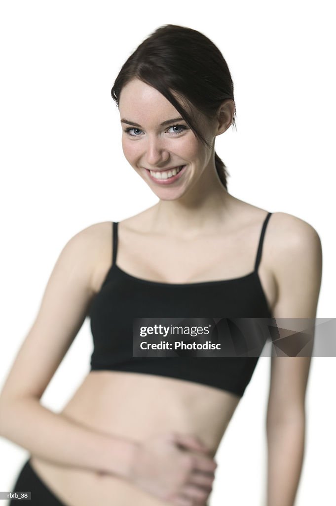 Medium shot of a young adult woman in a black exercise outfit as she smiles at the camera