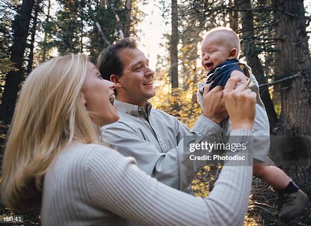 young couple hold baby in the air laughing - pinaceae stockfoto's en -beelden