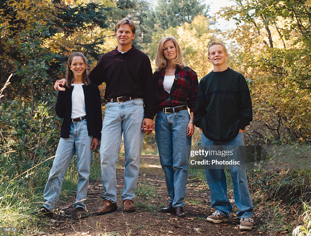 Family of four stand among trees