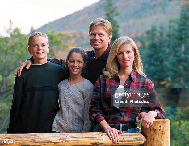 a family of four stands together on a cabin porch - pinaceae stockfoto's en -beelden