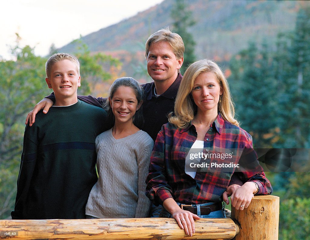 A family of four stands together on a cabin porch