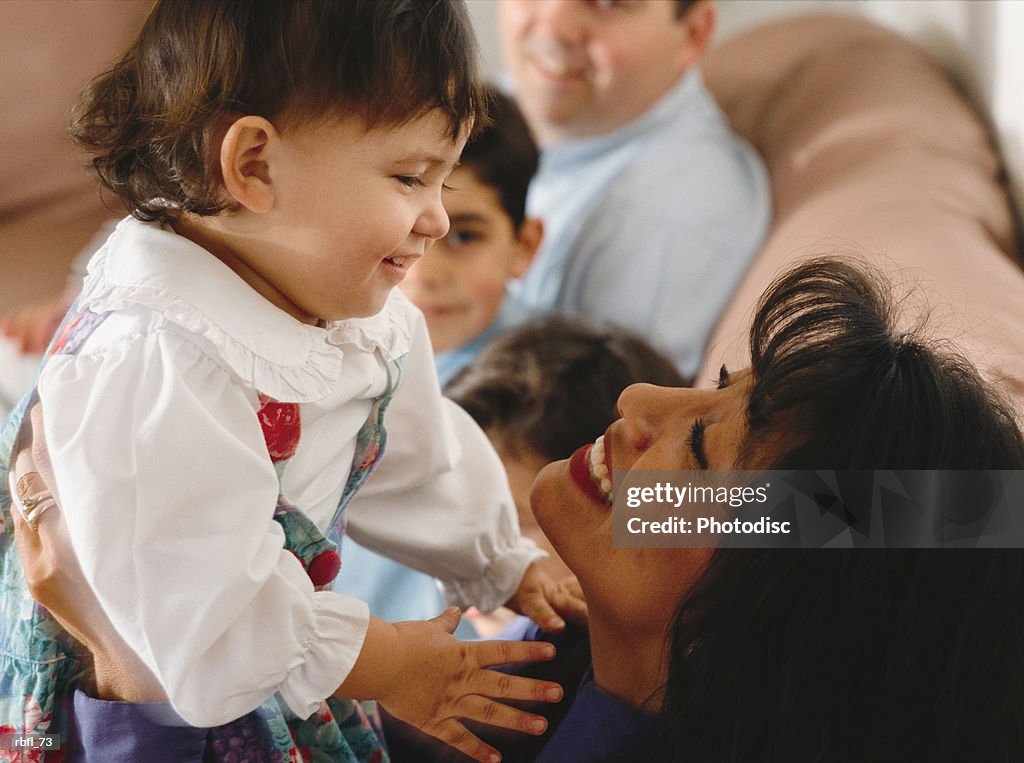 A mother holds her small daughter eye to eye at a family activity