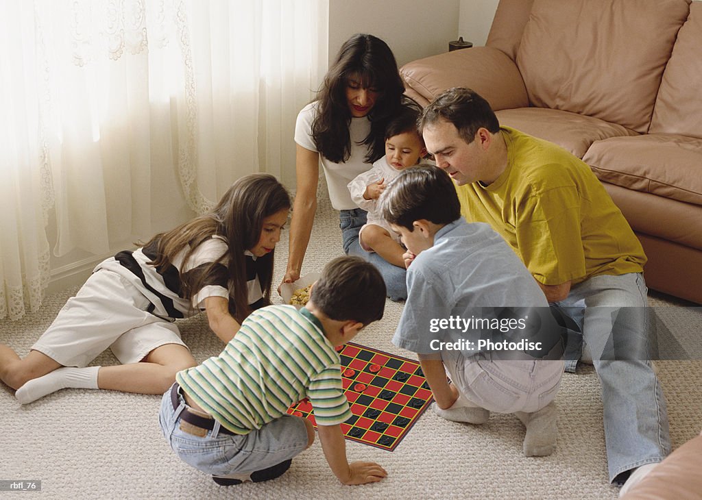 An ethnically mixed family sits in a circle playing a game