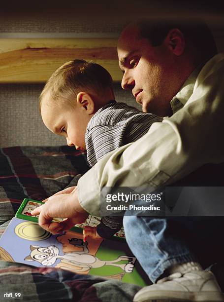 a father reads with his young son on the bed - bedtime stories stock-fotos und bilder