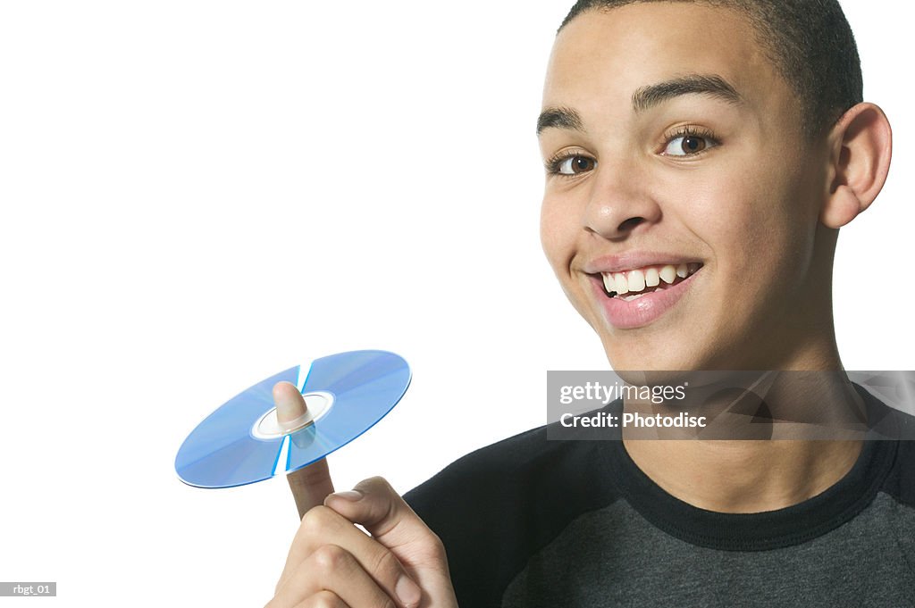 Close up shot of a teenage male as he holds up a cd on his finger