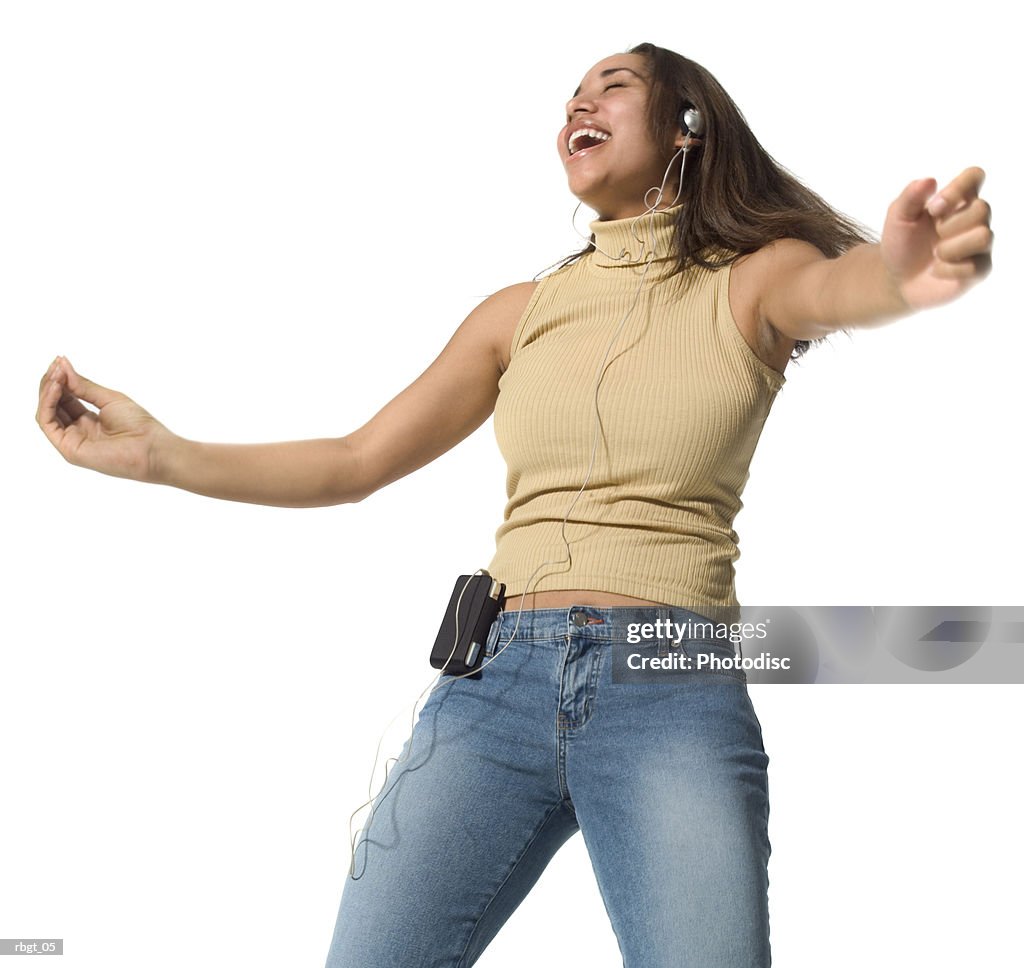 Medium shot of a teenage female as she listens to music over headphones and dances