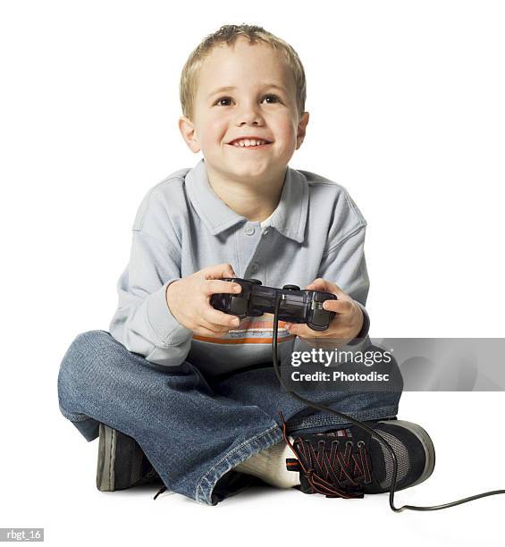 full body shot of a male child as he sits and uses a video game controler - uses stock pictures, royalty-free photos & images