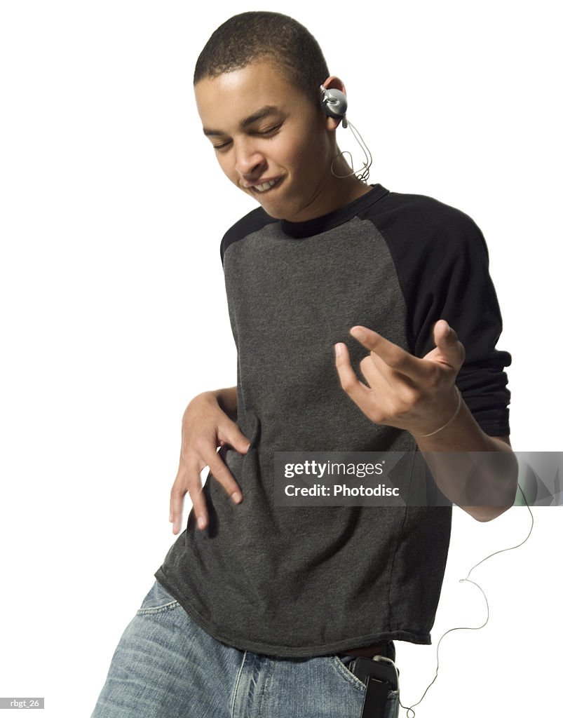 Medium shot of a teenage male as he dances while listening to music through headphones