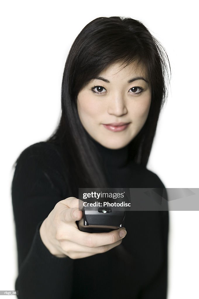 Medium shot of a young adult woman as she uses a television remote control