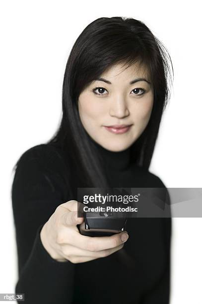 medium shot of a young adult woman as she uses a television remote control - uses stock pictures, royalty-free photos & images