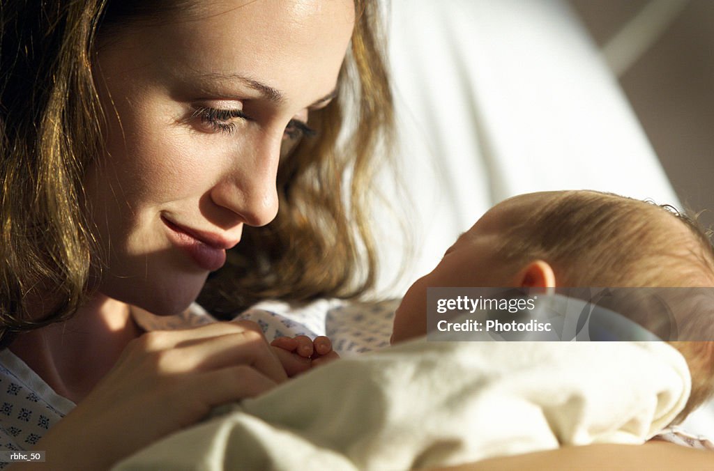 Close up as a young attractive mother looks lovingly at her newborn baby daughter