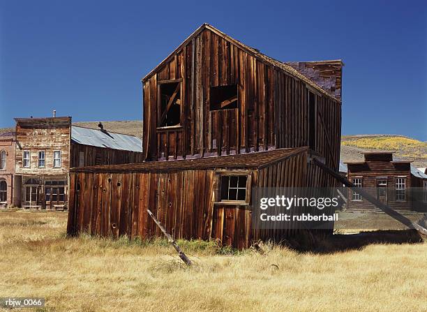 an old leaning wooden building in the desert ghost town of bodie california is propped up - verwaltungsbezirk mono county stock-fotos und bilder